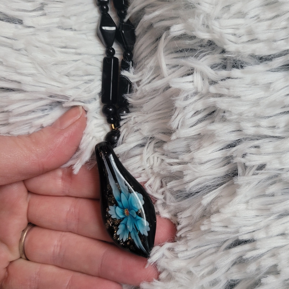 Glass bead necklace with blue flower pendant.